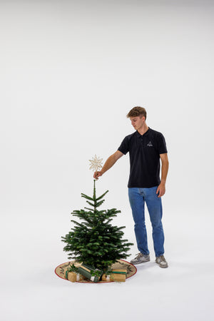 Dreng står og sætter stjerne på juletræ